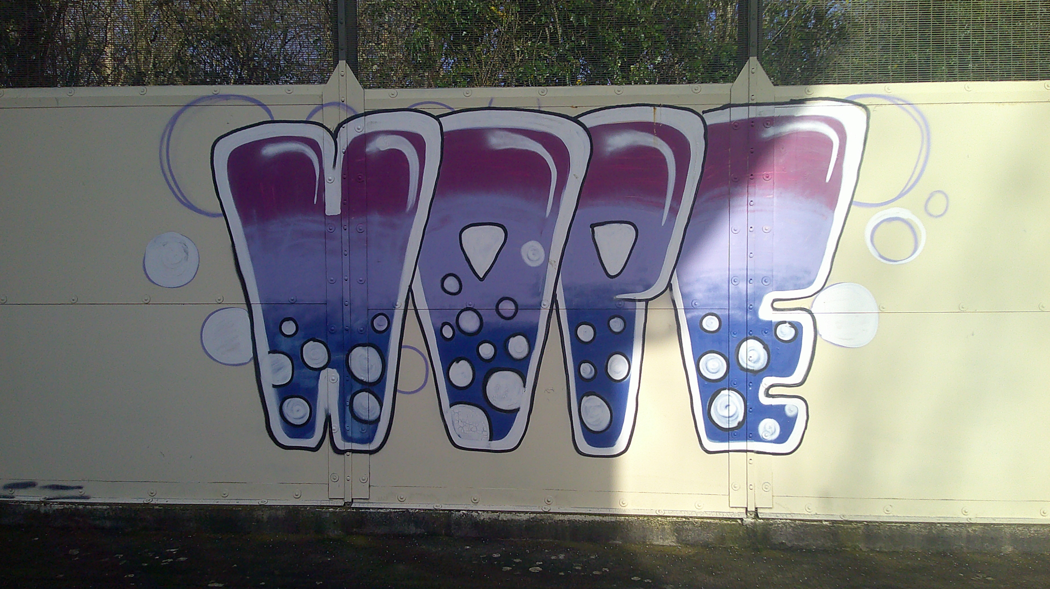 A wall with the word 'Hope' graffitied on it in all capital letters. The letters are ombre, going from purple to lilac to dark blue and with white bubbles rising from the bottom. There are also bubbles painted behind the letters.