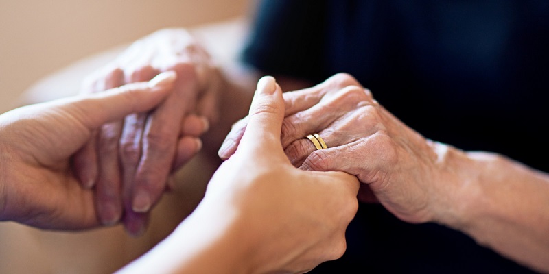 Young hands holding an old lady's hands