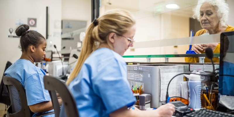 Nursing staff sitting at nurses' station at work with a patient