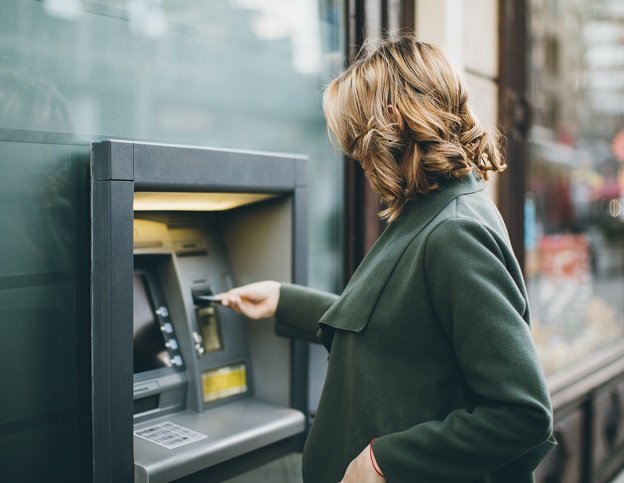 Woman putting bank card into an ATM